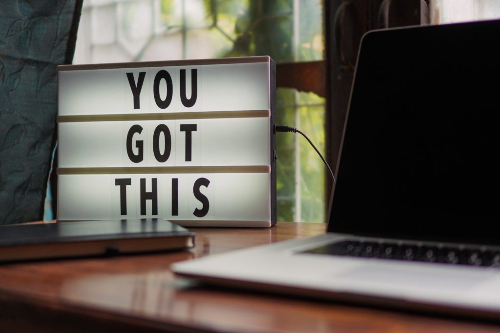 A lightboard and laptop on a desk. The lightboard has the words "You Got This". Photo by Prateek Katyal from Pexels